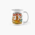 Glossy white ceramic coffee mug printed with cartoon Aussie lifeguard in surf-rescue outfit holding hot meat pie by ocean waves