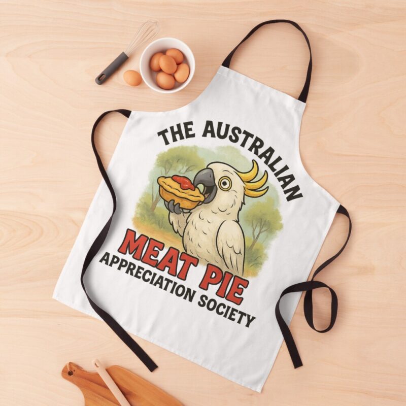 Adjustable kitchen apron printed with cartoon cockatoo eating meat pie topped with tomato sauce under eucalyptus bush scene