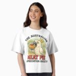 Boxy T-shirt printed with cartoon cockatoo eating meat pie topped with tomato sauce in eucalyptus bush background