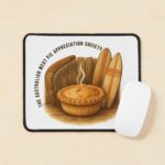 Desk mouse pad printed with golden Aussie meat pie framed by wooden boomerang and colourful surfboard on sandy beach backdrop