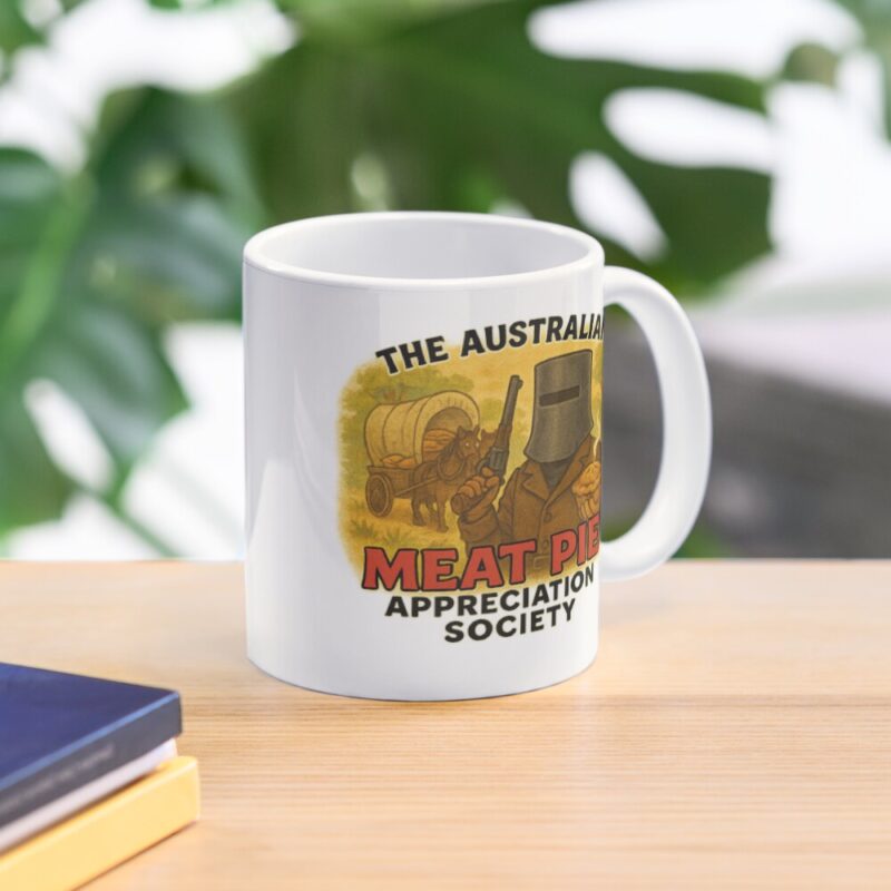 Glossy white ceramic coffee mug printed with cartoon Ned Kelly bushranger in helmet holding steaming Aussie meat pie